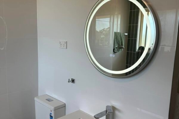 Backlit round LED mirror above a bathroom vanity – Marmont Electrical